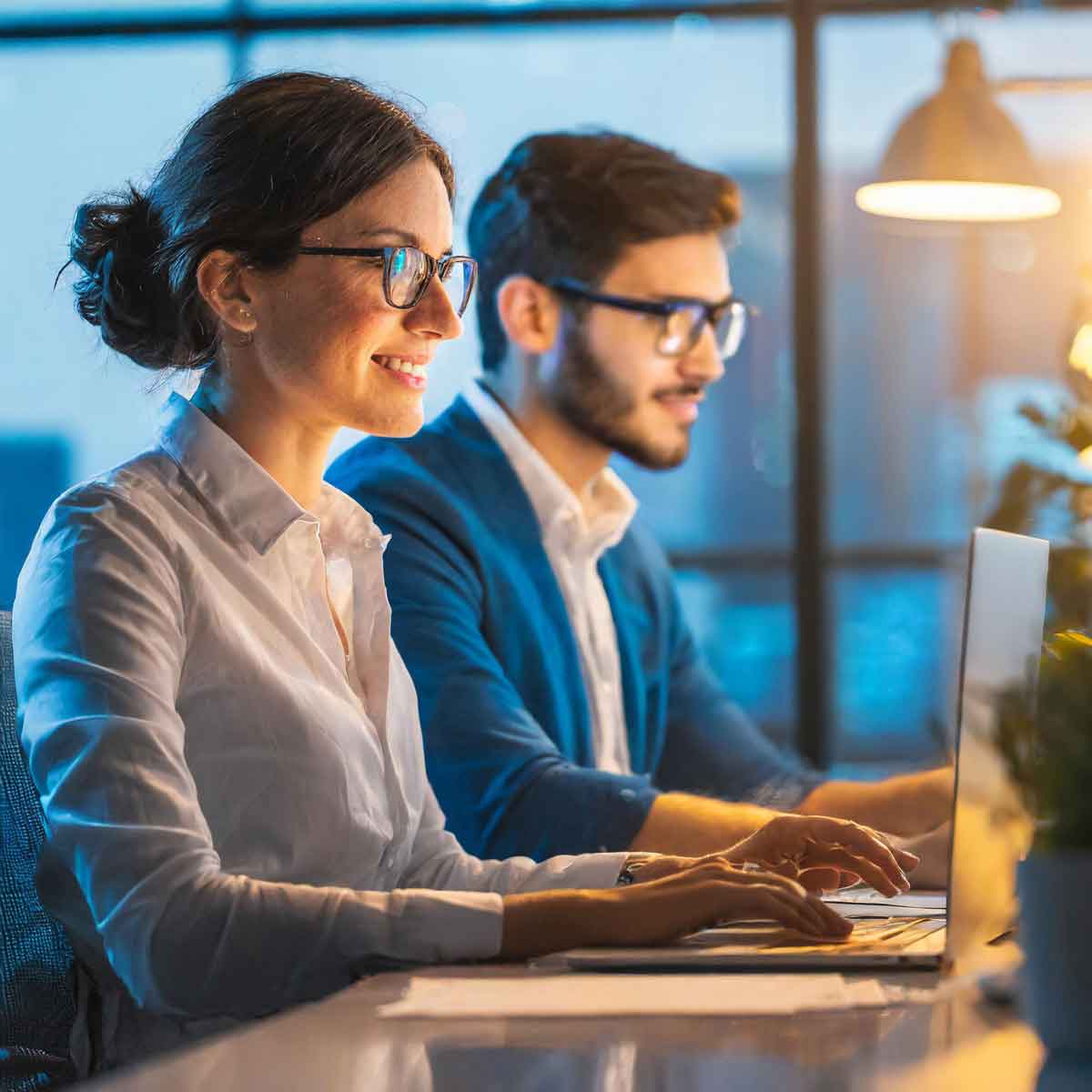 Two professionals working together on laptops at a desk